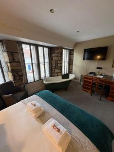 a bedroom with a bed and a bath tub and a television at The Covenanter Hotel in Falkland