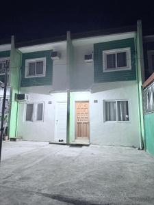 ein weiß-grünes Gebäude mit einer Holztür in der Unterkunft Sakura Crib at Xevera Calapan in Camilmil