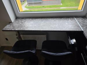 two chairs sitting next to a counter with a window at Baltijos Apartamentai, Self check-in, free parking in Klaipėda