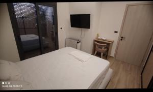 a bedroom with a white bed and a television at KANALI HOLIDAYS APARTMENT 5 in Preveza