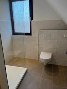 a bathroom with a toilet and a shower and a window at Ferienwohnung Bolle in Hooksiel +22 photos