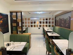 a dining room with tables and green booths at Hotel SK Chakan Pune in Dehu