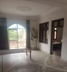 an empty living room with a large window and a table at Ravi Tomar Homestay in Phalauda