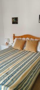 a bed with a striped comforter in a bedroom at Casa dos Avós Palma - Alcoutim in Alcoutim