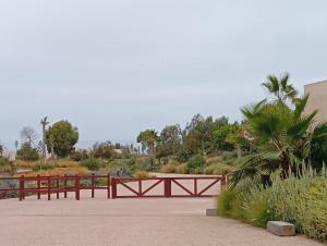 a park with a red fence and a palm tree at Tafoukt House in Aourir