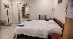 a bedroom with a bed with white sheets and a mirror at Anna Cottages Agonda in Agonda