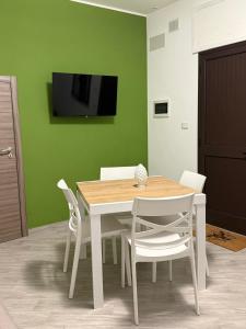 a dining room table with white chairs and a tv on a green wall at Casa Verdi in Carini