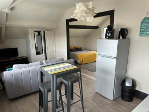 a living room with a couch and a table and a refrigerator at Private studio in Loft in Tarbes in Tarbes