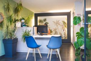 two blue chairs sitting at a desk with plants at Cit'Hotel L'Oasis d'Avignon in Villeneuve-lès-Avignon