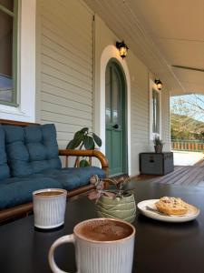 eine Veranda mit einer blauen Couch und Kaffeetassen auf einem Tisch in der Unterkunft Linos Cottage in Pouláta