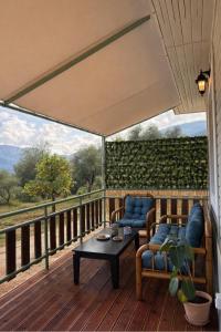 eine Veranda mit zwei Stühlen und einem Tisch auf einer Terrasse in der Unterkunft Linos Cottage in Pouláta