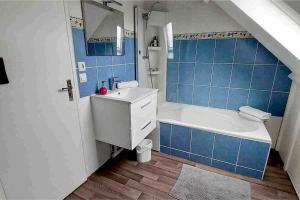 a bathroom with a tub and a sink and blue tiles at Exceptional duplex at Disneyland Paris in Serris +28 photos