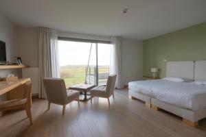 a bedroom with a bed and chairs and a large window at Logis Le Château de Sable in Porspoder