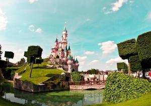 a castle in a park with a river in front of it at Exceptional duplex at Disneyland Paris in Serris