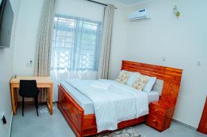 a bedroom with a bed and a desk and a window at Kibs Apartments in Dodoma
