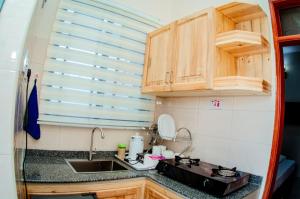 a small kitchen with wooden cabinets and a sink at Kibs Apartments in Dodoma