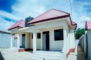 a small white building with a red roof at Kibs Apartments in Dodoma