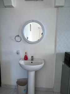 a white bathroom with a sink and a mirror at Skyview Bamburi Suites in Mombasa