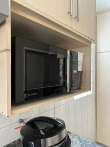 eine Mikrowelle in einer Küche mit einem Topf in der Unterkunft Master Home Digital QUARTOS COMPARTILHADOS in Barueri