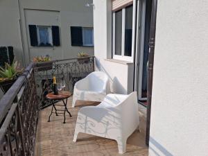 a balcony with two white chairs and a table at Gerry Home in Valmadrera