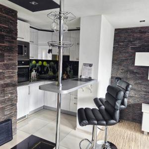a kitchen with white cabinets and a bar with black chairs at Black & White Komfortowe Apartamenty 2 km od Centrum in Racibórz +14 photos