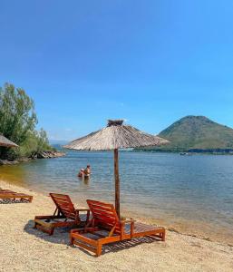 a group of chairs and an umbrella on a beach at Villa Piste - Skadar Lake in Virpazar