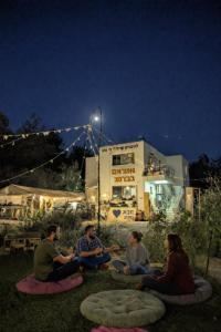 a group of people sitting on the grass at night at guest house אשראם בכרמל - אכסניה in Dāliyat el Karmil