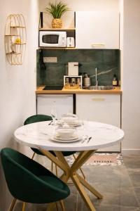 a kitchen with a table and two green chairs at La Chic Opéra - à 30 secondes min du Vieux-Port- Clim in Marseille