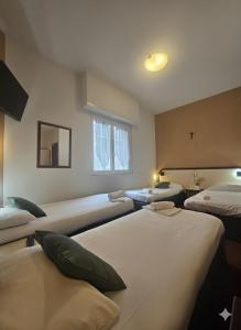 a room with three beds and a window at Hôtel Myosotis in Lourdes +31 photos