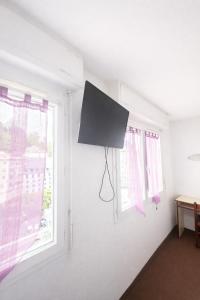 a room with two windows and a tv on the wall at Hôtel Myosotis in Lourdes