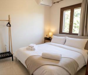 a bedroom with a large white bed with a window at Vignetta Mare 2BR Villa με Θέα & και Ιδιωτικό Πάρκινγκ in Ermoupoli