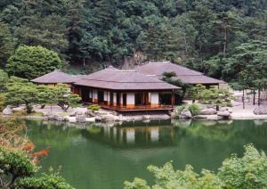 a house with a pond in front of it at ゲストハウス瓦町 in Takamatsu
