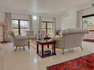 a living room with two chairs and a table at Miyanwe Guest House - Waterkloof in Pretoria +25 photos