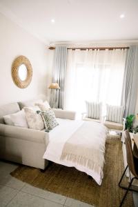 a white bedroom with a white couch and a window at The Halfway Homestead in Middelburg
