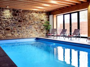 een zwembad met stoelen en een bakstenen muur bij Luscious Holiday Home in Waimes with Pool Sauna in Robertville