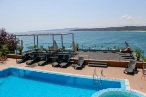 a swimming pool with chairs and a view of the water at Solinaria Boutique Hotel in Sozopol