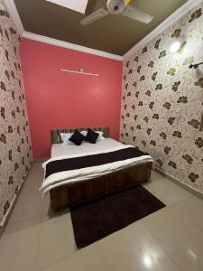 a bedroom with a bed with a red wall at Karuna Homestay in Ujjain