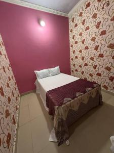 a small bedroom with a bed and a purple wall at Karuna Homestay in Ujjain +6 photos