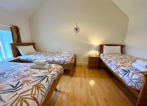 two twin beds in a room with wooden floors at Hidden Hills Waterville - Private Farmhouse in Waterville
