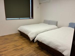 two beds in a room with a large window at Cottage Tasuki in Nakijin