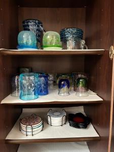 a shelf filled with different colored glass jars and plates at Cottage Tasuki in Nakijin