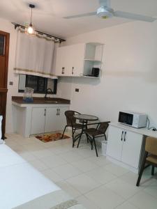 a kitchen with white cabinets and a table and chairs at Bluu Diani in Diani Beach