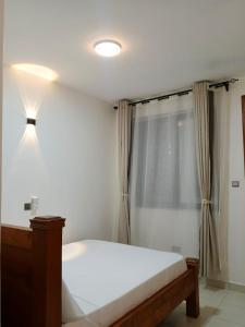 a bedroom with a white bed and a window at Bluu Diani in Diani Beach