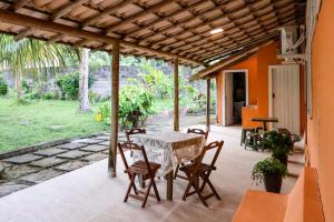 a patio with a table and chairs on it at Casa Coqueville - Charmosa, tranquila e cercada pela natureza em Itacaré in Itacaré