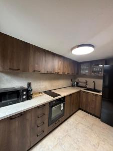 a kitchen with wooden cabinets and a sink and a microwave at Nenchova Guest House in Koprivshtitsa