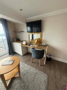 a room with a desk with a television on the wall at Porth Avallen Hotel in St Austell