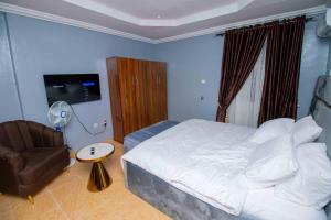 a bedroom with a white bed and a chair at Living Space Apartment in Ibadan +5 photos
