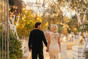 a bride and groom walking through a garden at Masseria Messapia Wine Resort & Spa Salento in Mesagne +100 photos