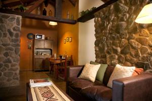 - un salon avec un canapé et un mur en pierre dans l'établissement Las Retamas Apart Boutique, à Sierra de la Ventana