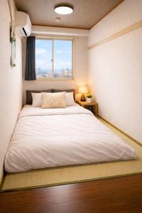 a bedroom with a large white bed with a window at 心斎橋難波関空直通 Ambers Hostel in Osaka